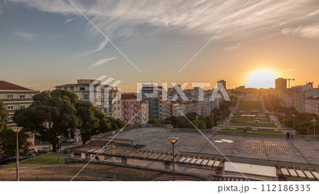 Panorama showing sunset over lawn at Alameda Dom Afonso Henriques and the Luminous Fountain aerial timelapse in Lisbon. 112186335