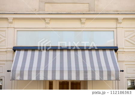 Gray and white awning over the windows on the white wall Gray and white awning over the windows on the white wall 112186363