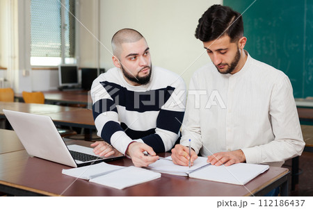 Guys working on student project at desk 112186437