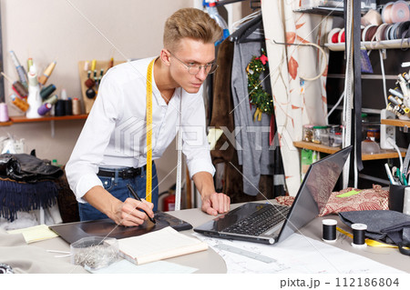 Tailor using laptop and graphics tablet 112186804