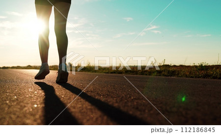 silhouette sports girl running along road sunset, legs close-up, outdoor sports training, outdoors girl sportswear training, sun setting, confident motivated beautiful sportswoman, female power silhouette sports girl running along road sunset, legs close-up, outdoor sports training, outdoors girl sportswear training, sun setting, confident motivated beautiful sportswoman, female power 112186845