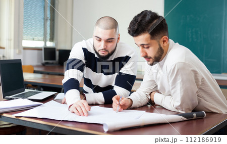 Students working with laptop at desk 112186919