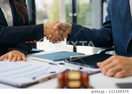 Lawyer shaking hands with client after discussing final contract agreement. 112189374