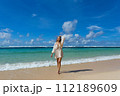 Young woman walks barefoot on the beach 112189609