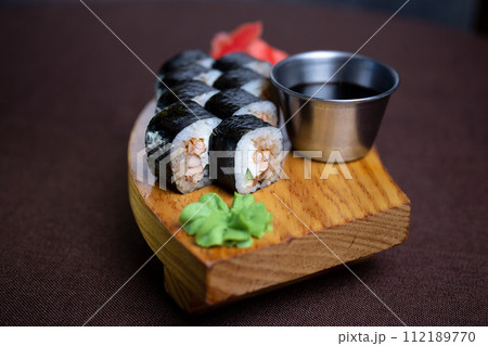 Sushi rolls served on a wooden plate with chopsticks and soy sauce. Isolated on a white background. 112189770