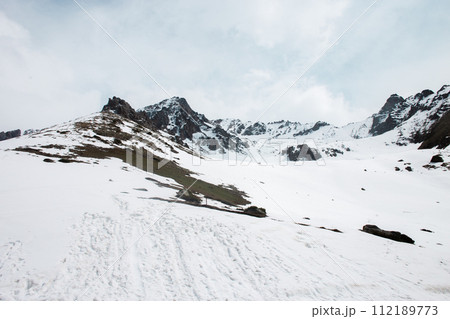 Snow-capped mountain peaks and rocks in the distance with snow-covered hills in the foreground 112189773