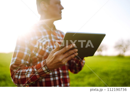 Farmer working with digital tablet in field at sunset. Checking wheat field. Agriculture concept. 112190736