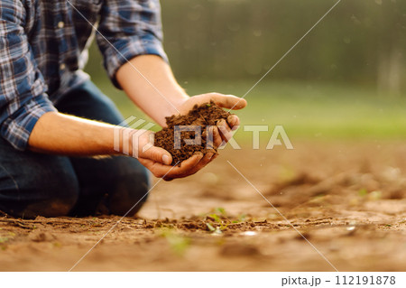 Close-up of a farmer's strong hands on a black field. Concept of gardening, ecology. 112191878