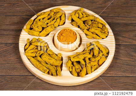 Turmeric powder and dried turmeric root top view. Turmeric powder and dried turmeric root top view. 112192479