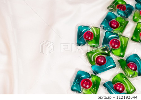 Lots of laundry pods capsule detergent on satin fabric, copy space for text. 112192644