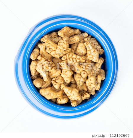 A treat for cats and kittens is a fish-shaped catnip cookie in a blue bowl, copy space for text. 112192665