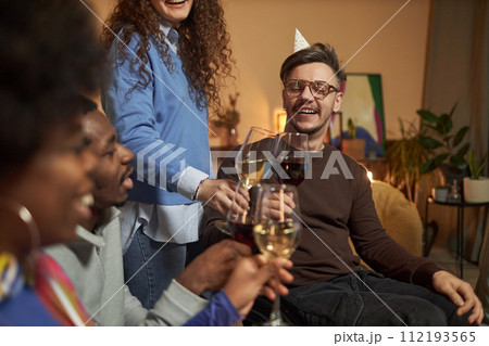 Portrait of man with disability clinking wine glasses while toasting with friends and celebrating together 112193565