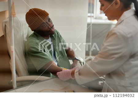 Portrait of African American man receiving chemotherapy treatment in procedure room at clinic behind glass copy space 112194032