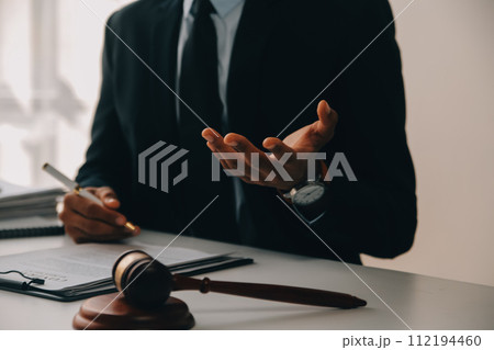 Justice and Law concept. Legal counsel presents to the client a signed contract with gavel and legal law or legal having team meeting at law firm in background 112194460