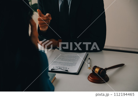 Justice and Law concept. Legal counsel presents to the client a signed contract with gavel and legal law or legal having team meeting at law firm in background Justice and Law concept. Legal counsel presents to the client a signed contract with gavel and legal law or legal having team meeting at law firm in background 112194465