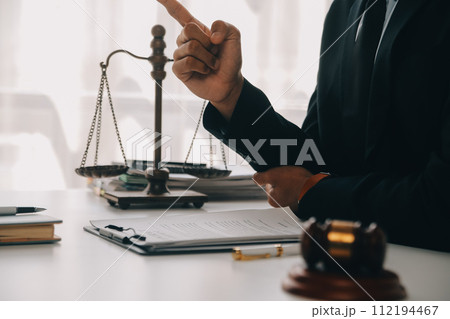 Justice and Law concept. Legal counsel presents to the client a signed contract with gavel and legal law or legal having team meeting at law firm in background 112194467