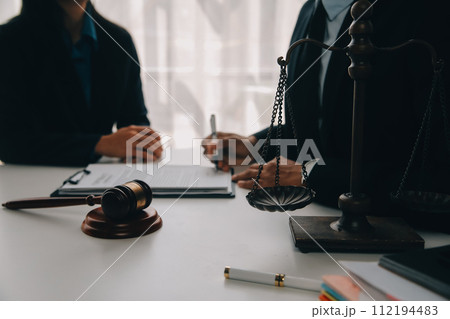 Justice and Law concept. Legal counsel presents to the client a signed contract with gavel and legal law or legal having team meeting at law firm in background 112194483