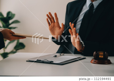 Justice and Law concept. Legal counsel presents to the client a signed contract with gavel and legal law or legal having team meeting at law firm in background Justice and Law concept. Legal counsel presents to the client a signed contract with gavel and legal law or legal having team meeting at law firm in background 112194491