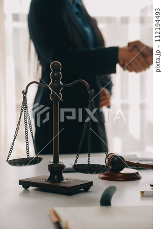 Justice and Law concept. Legal counsel presents to the client a signed contract with gavel and legal law or legal having team meeting at law firm in background Justice and Law concept. Legal counsel presents to the client a signed contract with gavel and legal law or legal having team meeting at law firm in background 112194493