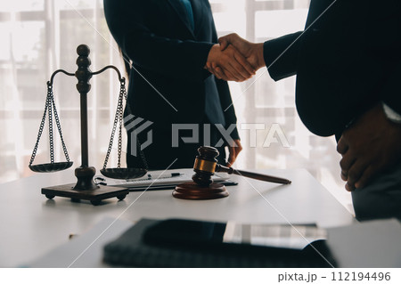 Justice and Law concept. Legal counsel presents to the client a signed contract with gavel and legal law or legal having team meeting at law firm in background 112194496