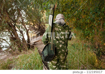 man gray-haired fisherman is looking for a place to fish, goes forward, the view from behind. Back. Beautiful forest, river bank, comes home, copy space, outdoor. Walking, hunting. close up 112195017