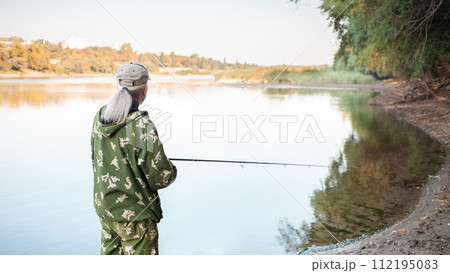 eldest on bank of river, a man with a fishing rod fishing, beautiful nature, autumn. An old man rests and loves his hobby. Active healthy lifestyle, outdoor. 112195083