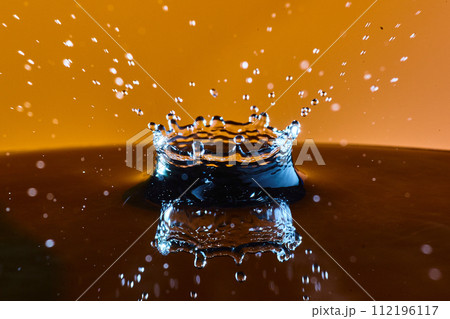 Water Droplet Crown with Golden Backdrop, High-Speed Side View 112196117