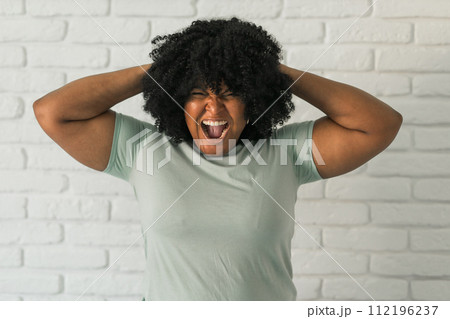 Angry african american woman screaming on brick background. Bad aggressive emotions and premenstrual syndrome or pms concept 112196237