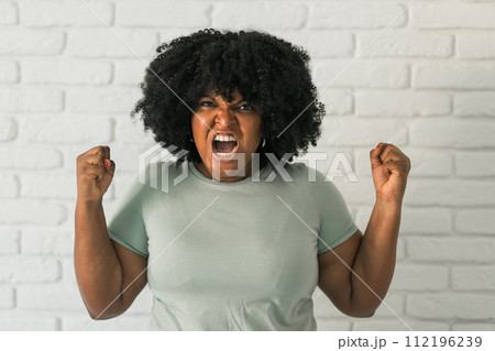 Angry african american woman screaming on brick background. Bad aggressive emotions and premenstrual syndrome or pms concept 112196239