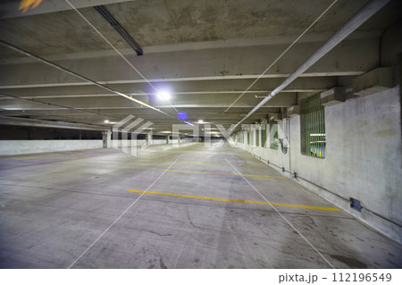Spacious Empty Parking Garage with Fluorescent Lighting and Green Windows 112196549