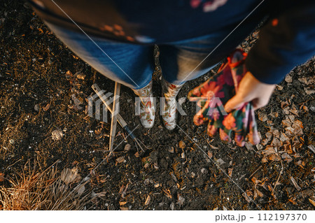 spring planting seeds in the ground, young woman prepares the soil and plants seeds from her hand in the ground spring planting seeds in the ground, young woman prepares the soil and plants seeds from her hand in the ground 112197370