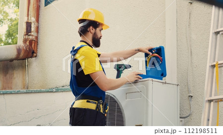 Licensed engineer commissioned by home owner, preparing for yearly air conditioner maintenance. Capable technician unpacking toolbox with professional equipment needed to fix broken draining lines 112198511