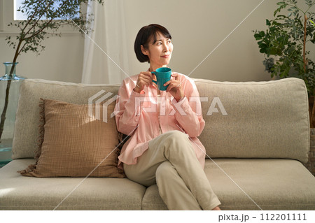 ソファーでコーヒーを飲む女性 112201111