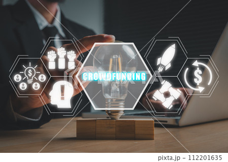 Crowdfunding concept, Businessman hand touching lightbulb on office desk with crowdfunding icon on virtual screen. Crowdfunding concept, Businessman hand touching lightbulb on office desk with crowdfunding icon on virtual screen. 112201635