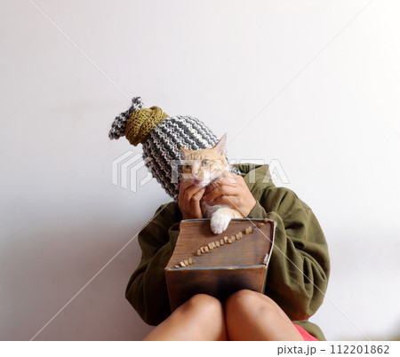 woman that head cover scarf, look like pineapple, hold cat in hand with old big book 112201862