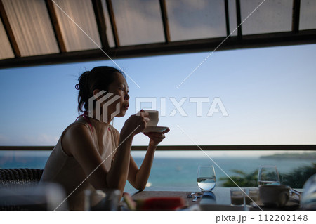 海沿いのレストランでコーヒーを飲む女性 112202148
