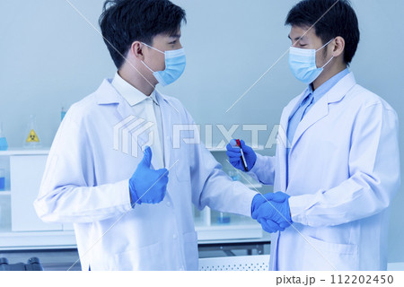 Close up Two asian scientist men team partner shake hands together. Crop Men researcher holding chemistry science tube experiment biotech sample in laboratory. Close up hand corporate partnership 112202450