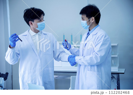 Two asian scientist men team partner shake hands together. Men researcher holding chemistry science tube experiment biotech antibody sample in laboratory. Close up hand corporate coworker partnership Two asian scientist men team partner shake hands together. Men researcher holding chemistry science tube experiment biotech antibody sample in laboratory. Close up hand corporate coworker partnership 112202468