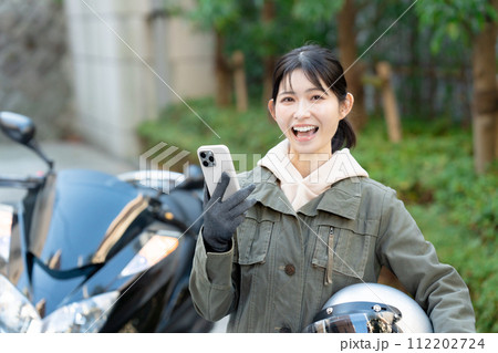 スマホを持つバイク女子 112202724