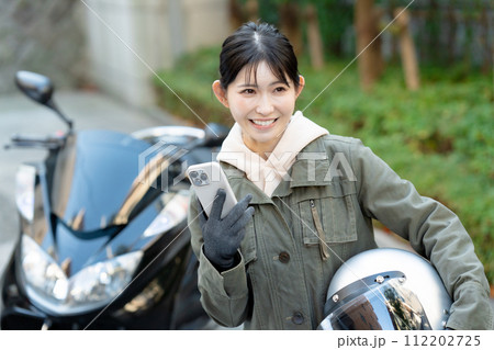 スマホを持つバイク女子 112202725