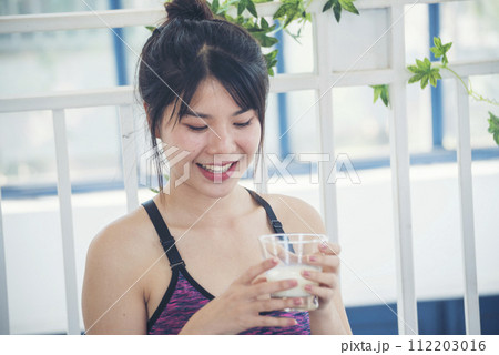 Women hands holding white glass of milk pouring from bottle. Asian women smile laugh look at camera health care home fitness lifestyle. Beautiful female drinking fresh milk low-fat dairy free lactose Women hands holding white glass of milk pouring from bottle. Asian women smile laugh look at camera health care home fitness lifestyle. Beautiful female drinking fresh milk low-fat dairy free lactose 112203016