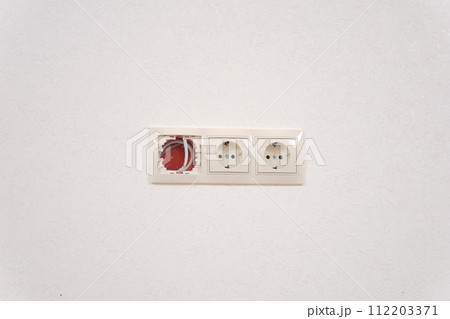 Disassembled, torn out electrical socket with bare wires in the bathroom. The concept of the danger of electric shock damage from a broken outlet. Repair and restoration of the home power grid. 112203371