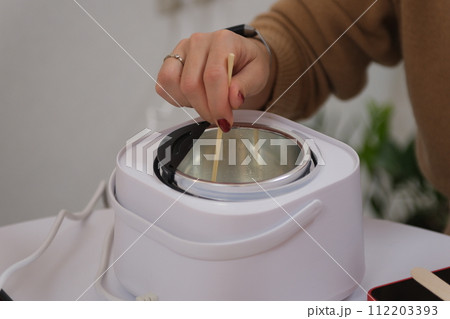 The process of making a massage candle using ingredients oils and wax measure weigh stir add close-up of women's hands. food thermometer measure wax temperature women's party women witches witchcraft 112203393