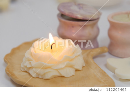 The lighter ignites a candle, light a candle hand with match sets fire to scented pink wax candle on a gray background 112203465