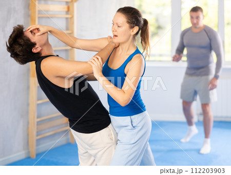 Guy paired up with woman to perform effective impact on pain points while learning self-defense. Guy paired up with woman to perform effective impact on pain points while learning self-defense. 112203903
