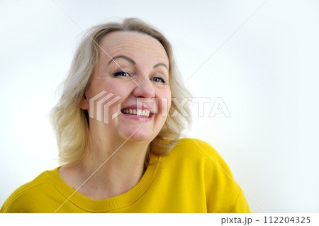 Happy smiling beautiful cute lovely blonde senior woman with beauty clean skin in casual wear isolated on yellow background. Healthcare and cosmetology concepts. Pensioner and mature people Happy smiling beautiful cute lovely blonde senior woman with beauty clean skin in casual wear isolated on yellow background. Healthcare and cosmetology concepts. Pensioner and mature people 112204325