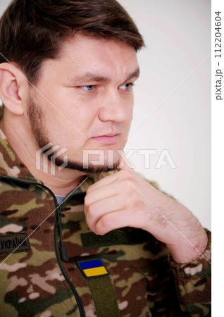 Ukrainian soldier leaned his head on hand and thought uniform inscription on jacket armed forces of Ukraine pain and sadness in his eyes. the war changed life. Russia attacked Ukraine 112204604