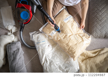 The girl pumps out air with a vacuum cleaner from a vacuum bag with clothes.  The girl pumps out air with a vacuum cleaner from a vacuum bag with clothes.  112204987