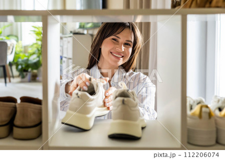 Woman arrangement sneakers on shoes closet shelf comfortable storage organizing method at home 112206074