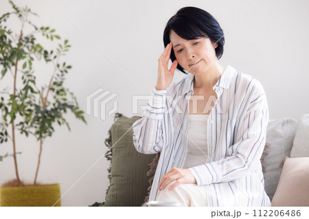 体調不良 頭痛で痛い頭をおさえるミドル女性 体調不良 頭痛で痛い頭をおさえるミドル女性 112206486